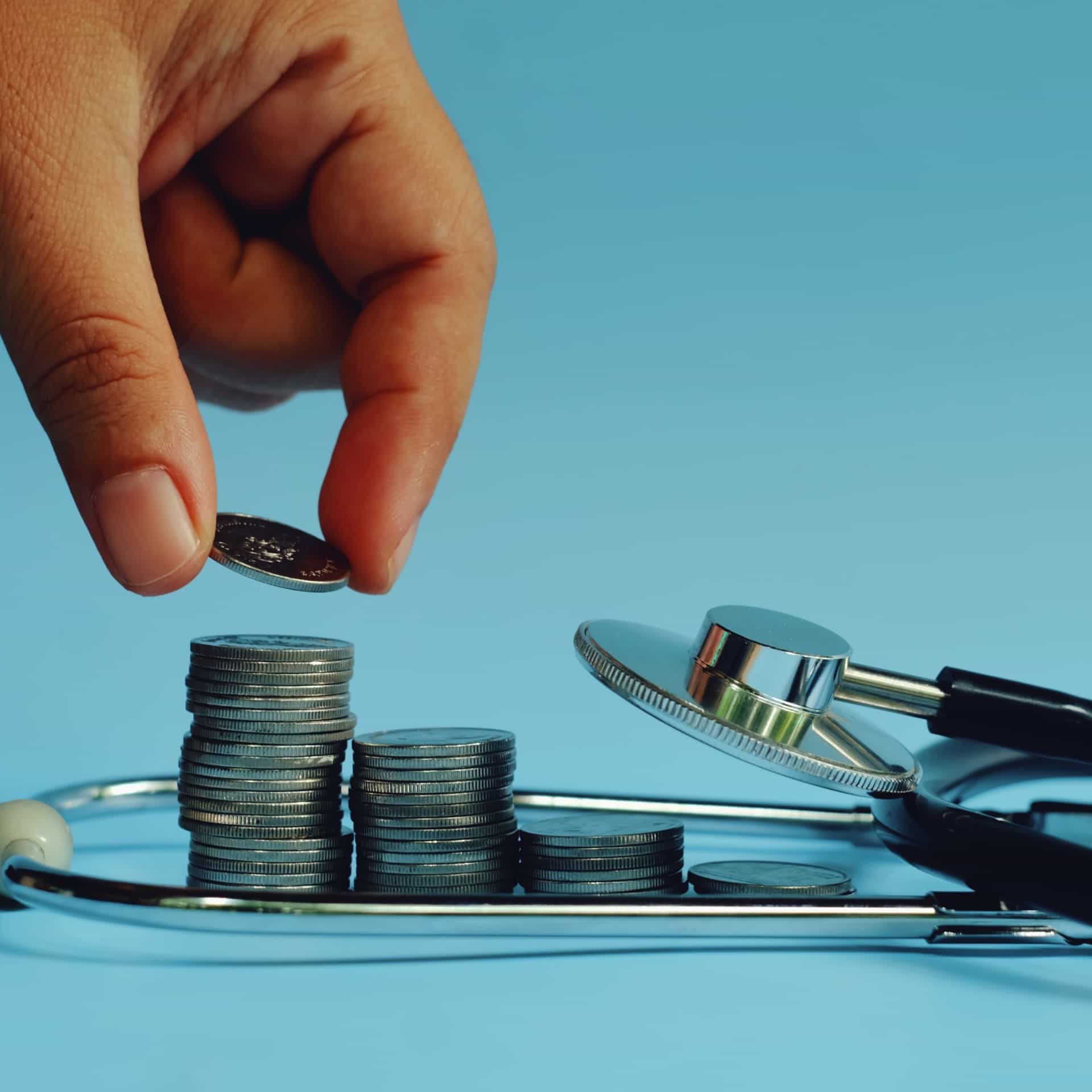 Coins stacked next to a stethoscope