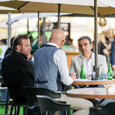 3 males sitting at a table with food and beverage at WHX Dubai