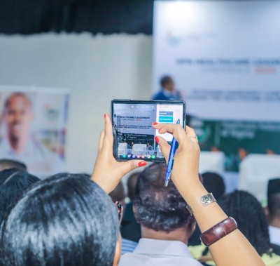 Conference attendee taking a photo on a smartphone at WHX Lagos
