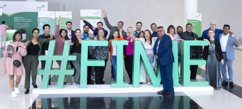 Delegates standing by the event sign #FIME