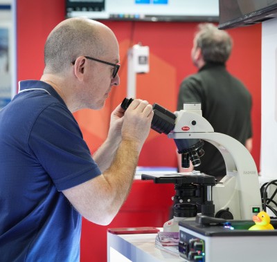 Exhibition attendee looking at a microscope at WHX Labs Dubai