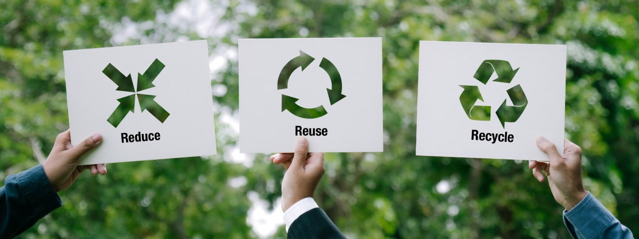 Signs held up saying Reduce Reuse Recycle