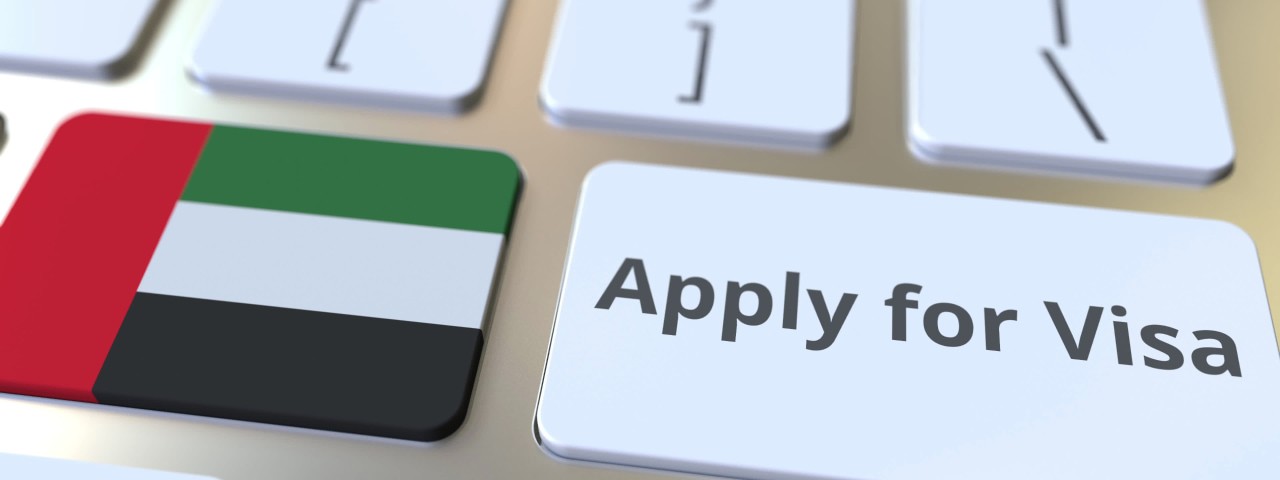 Flag of the United Arab Emirates on a computer keyboard next to a button that says Apply for Visa.